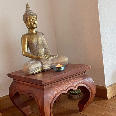 Foto von goldfarbener Buddha-Figur auf Holzbank